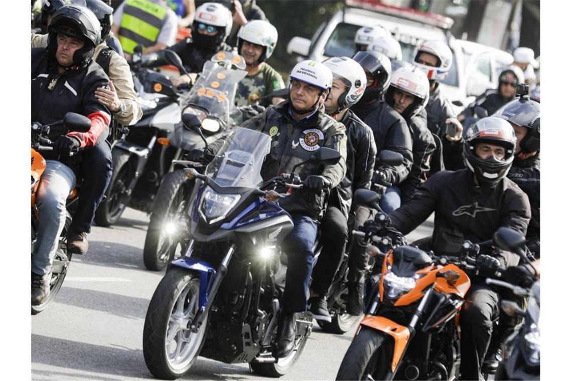 Bolsonaro in der Karawane von Motorradfahrern auf ihrem Weg durch Sao Paulo. Erst vor drei Wochen hatte Bolsonaro ohne Mund-Nasen-Schutz an einer Motorradrundfahrt durch die Millionenmetropole Rio de Janeiro teilgenommen und eine Rede vor seinen Anhängern gehalten. Foto: Marcelo Chello/AP/dpa