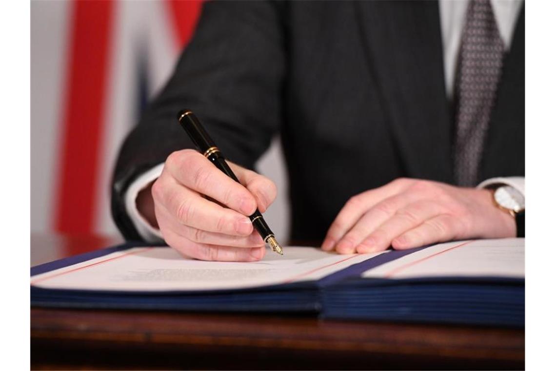 Johnsons Märchen vom guten Brexit Boris Johnson unterzeichnet im Dezember 2020 den Brexit-Handelspakt mit der Europäischen Union. Foto: Leon Neal/PA Wire/dpa
