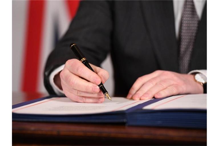 Boris Johnson unterzeichnet im Dezember 2020 den Brexit-Handelspakt mit der Europäischen Union. Foto: Leon Neal/PA Wire/dpa
