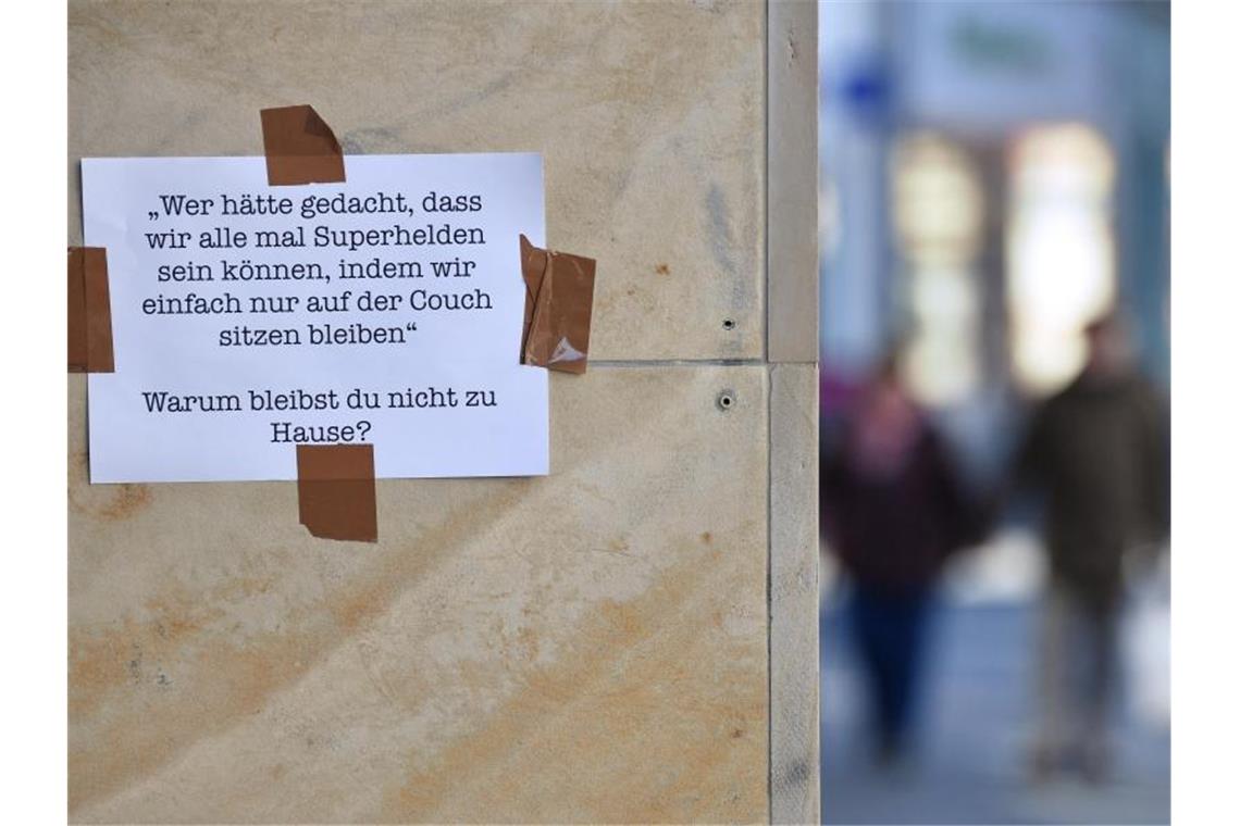 Botschaft auf einem Blatt Papier an einer Hauswand in Erfurt: "Warum bleibst Du nicht zu Hause?". Foto: Martin Schutt/dpa-Zentralbild/dpa