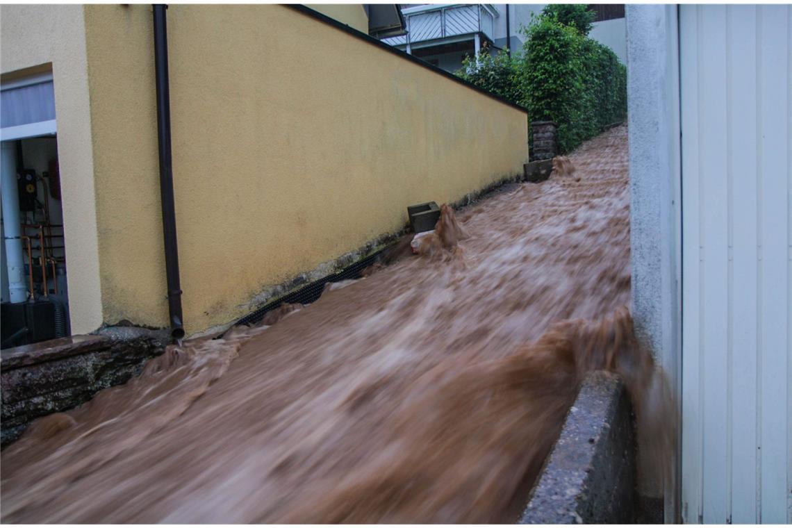 Was zahlt die Versicherung im Schadensfall? Braune Wassermassen rauschen im baden-württembergischen Altensteig über eine Treppe nach unten nach heftigen Unwettern.