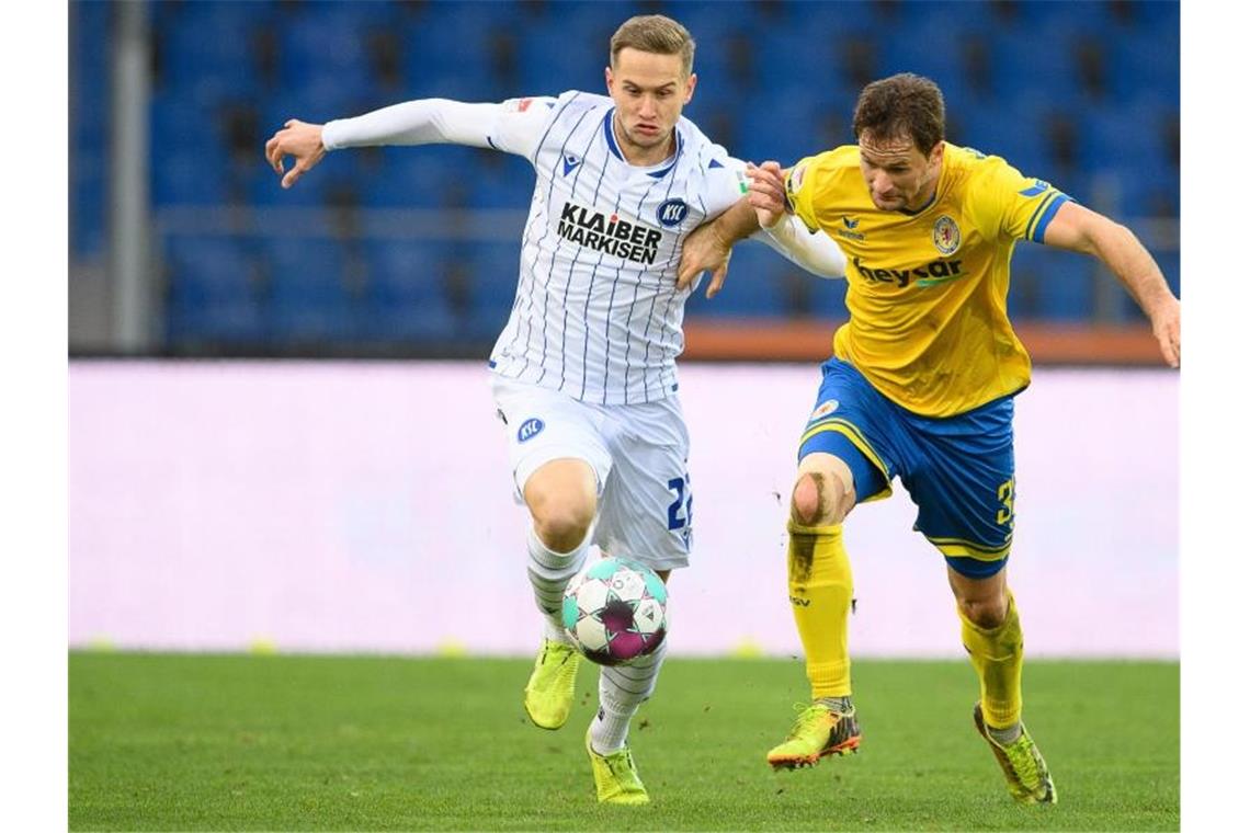 Braunschweigs Nick Proschwitz (r) spielt gegen Karlsruhes Christoph Kobald. Foto: Swen Pförtner/dpa