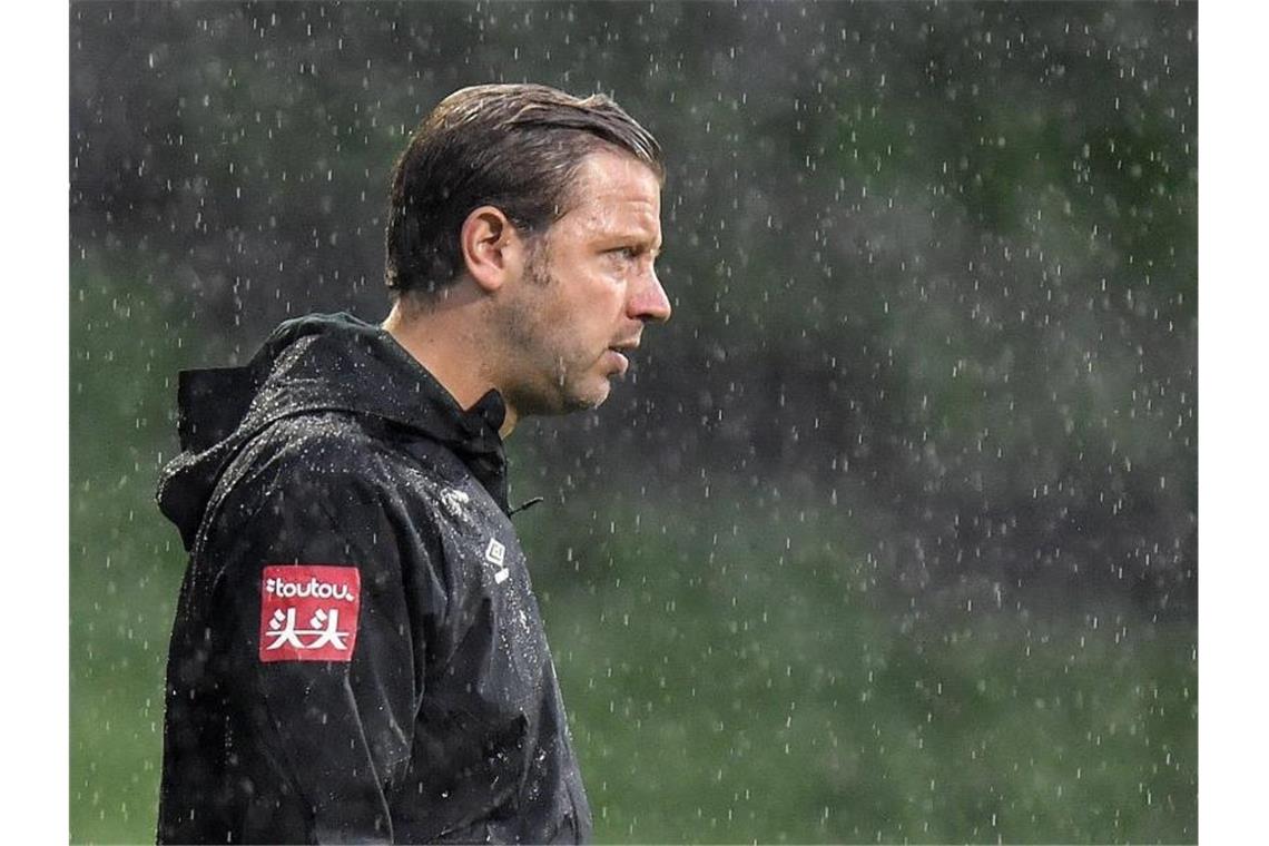 Bremens Cheftrainer Florian Kohfeldt steht im Regen. Foto: Martin Meissner/AP POOL/dpa