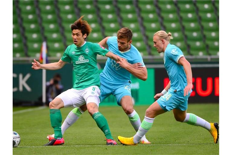 Bremens Yuya Osako (l) im Zweikampf mit Wolfsburgs Marin Pongracic (M) und Xaver Schlager. Foto: Patrik Stollarz/AFP/Pool/dpa