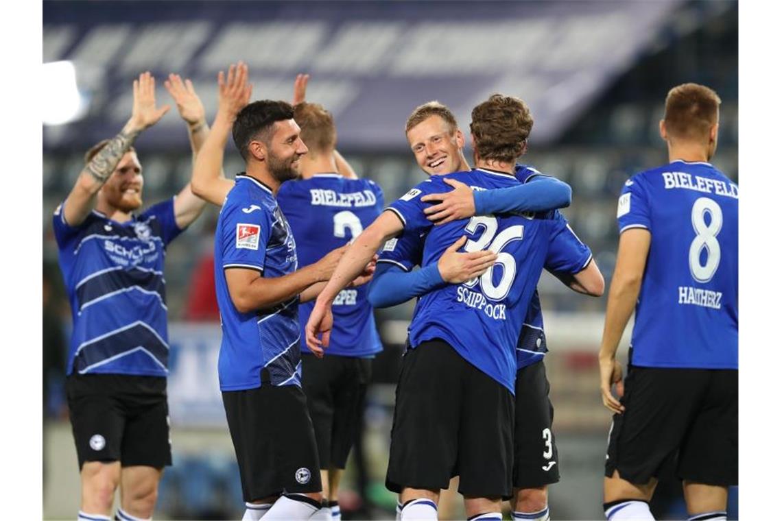 Brian Behrendt (2.vr) von Arminia Bielefeld feiert mit Sven Schipplock und weiteren Mitspielern den Sieg. Foto: Friso Gentsch/dpa-pool/dpa