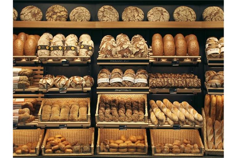 Brote verschiedenster Sorten liegen in Körben und auf Regalen. Foto: picture alliance/Paul Knecht/dpa/Symbolbild