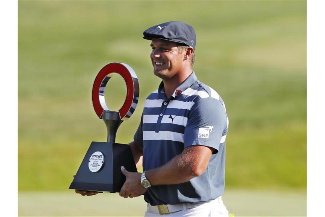 Bryson DeChambeau hält die Trophäe des Golfturniers Rocket Mortgage Classic in den Händen. Foto: Carlos Osorio/AP/dpa