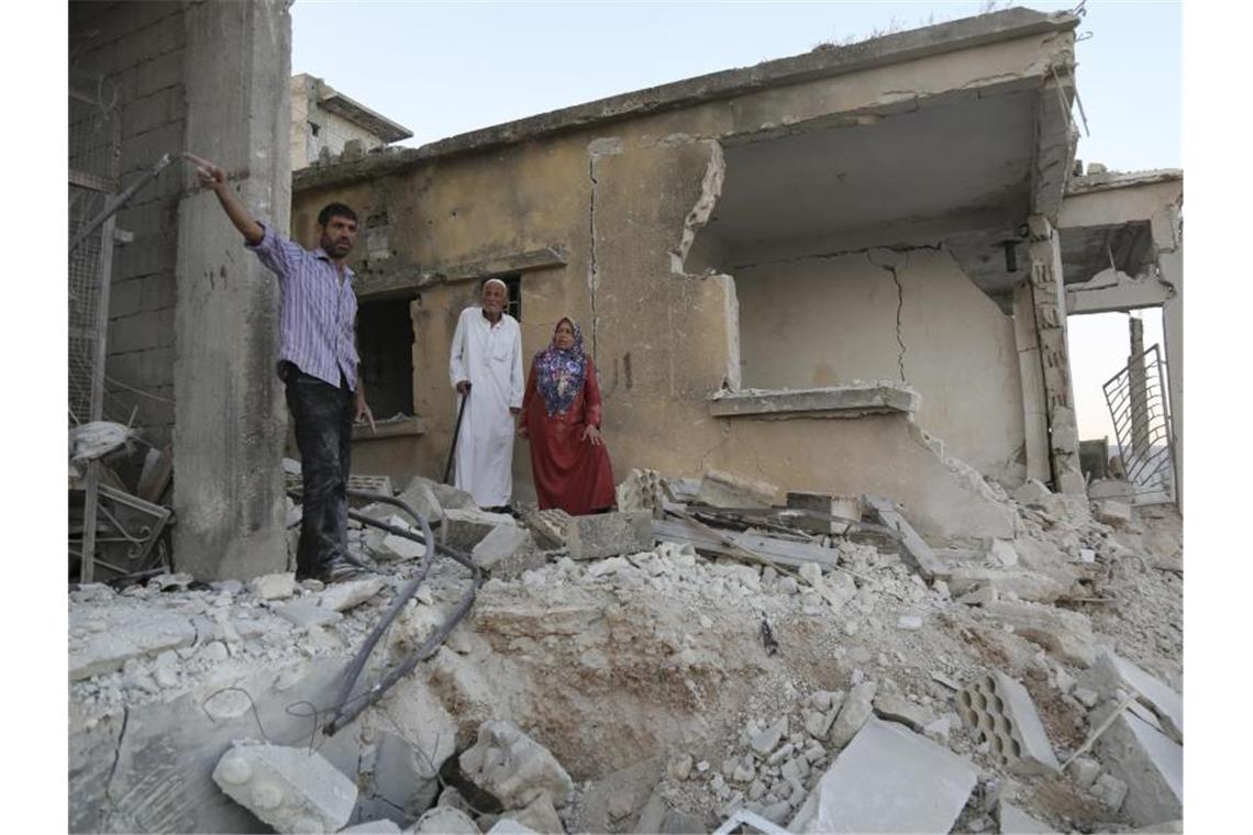 Bürger begutachten den Schaden an einem Haus, das bei Luftangriffen auf den Ort Muhambai zerstört wurde. Bei den Angriffen auf Syriens letztes großes Rebellengebiet um die Stadt Idlib sind Aktivisten zufolge 13 Menschen getötet worden. Foto: Anas Alkharboutli