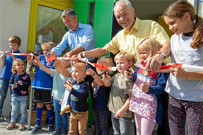 Bürgermeister Ian Schölzel (links) und Architekt Herbert Häußer zerschneiden mit tatkräftiger Unterstützung der Kinder symbolisch das Band zur offiziellen Einweihung des generalsanierten Kindergartens Oberweissach. Fotos. A. Becher