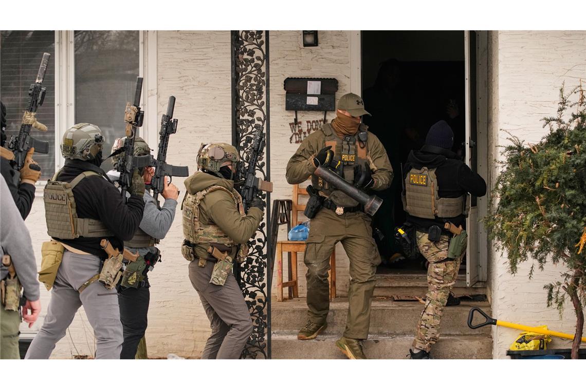 Bundesbeamte der Einwanderungsbehörde ICE bereiten sich darauf vor, ein Haus zu betreten, um eine Verhaftung vorzunehmen.