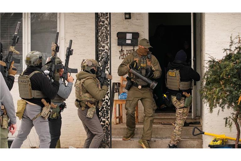 Bundesbeamte der Einwanderungsbehörde ICE bereiten sich darauf vor, ein Haus zu betreten, um eine Verhaftung vorzunehmen.