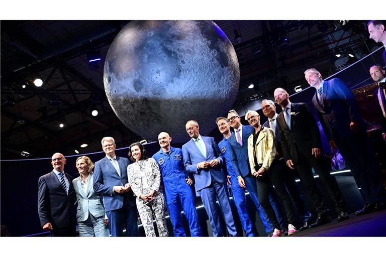 Bundeskanzler Friedrich Merz (6.v.l, CDU) steht unter anderem mit den beiden Esa-Astronauten Alexander Gerst (5.v.l) und Matthias Maurer (7.v.l) während eines Rundgangs auf der Internationalen Luft- und Raumfahrtausstellung (ILA).