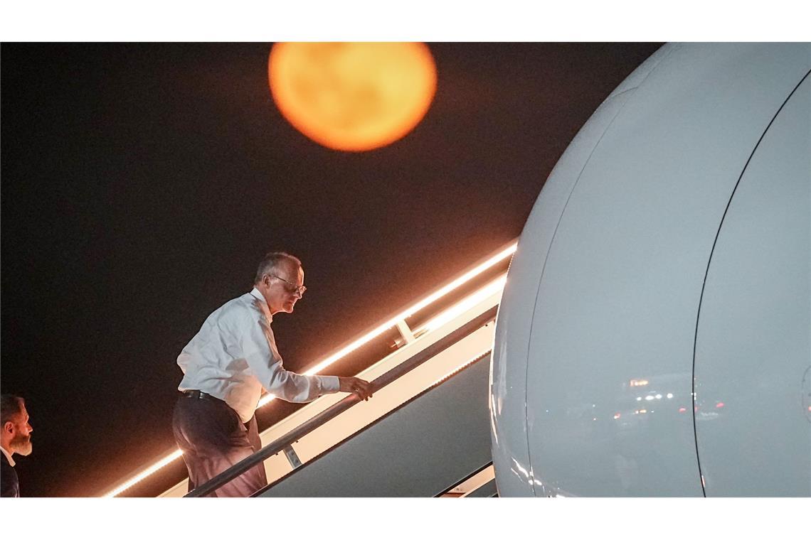 Bundeskanzler Friedrich Merz geht die Gangway vor dem aufgehenden Mond hinauf.