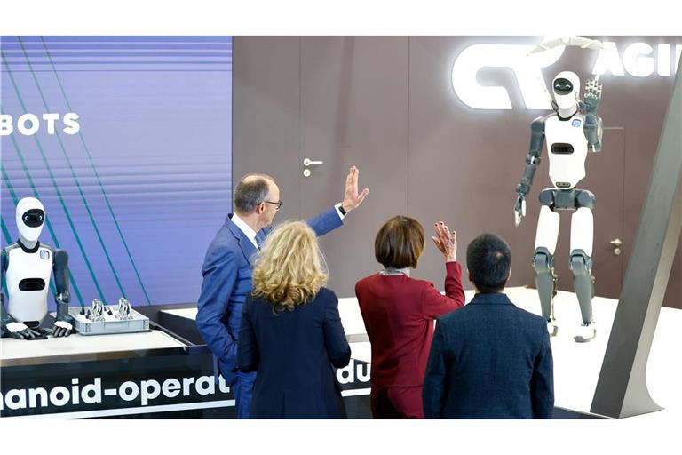 Bundeskanzler Friedrich Merz winkt einem Roboter zu – die Zukunft winkt zurück.
