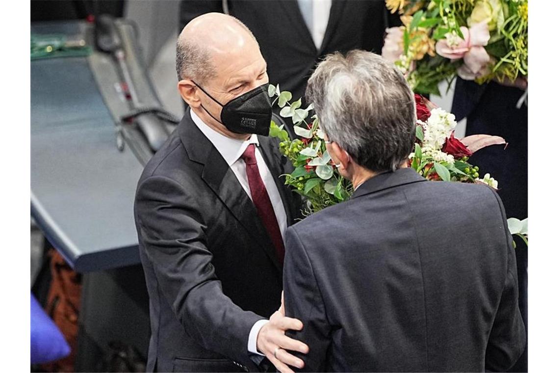 Bundeskanzler Olaf Scholz (l) erhält vom SPD-Fraktionschef Rolf Mützenich einen Blumenstrauß. Foto: Michael Kappeler/dpa