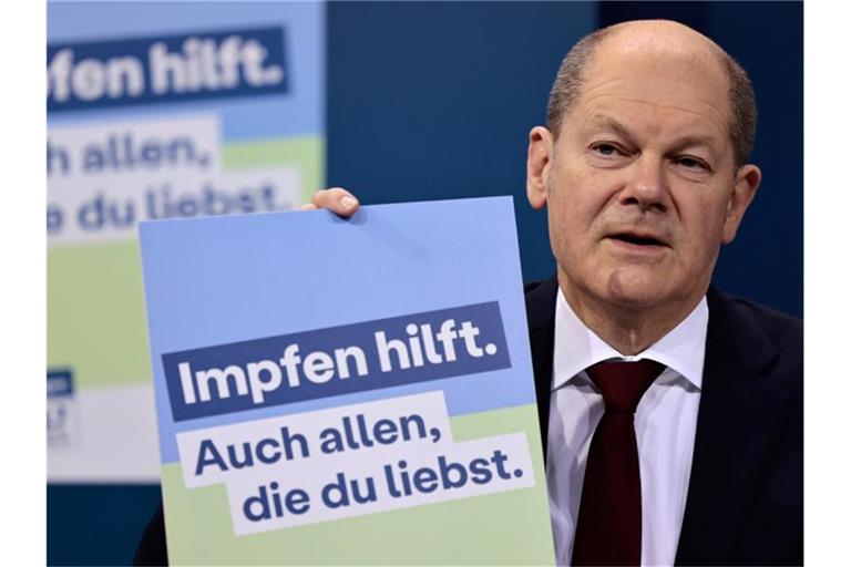 Bundeskanzler Olaf Scholz präsentiert ein Plakat aus der neuen Impfkampagne. Foto: Hannibal Hanschke/POOL AP/dpa