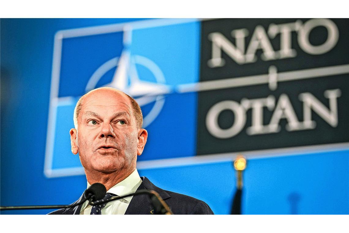 Was Trump von den Römern lernen könnte Bundeskanzler Olaf Scholz vor dem Emblem der Nato