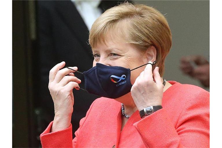 Bundeskanzlerin Angela Merkel (CDU) nimmt im Bundesrat ihre Mund- und Nasenschutzmaske ab, bevor sie eine Rede zu Zielen der EU-Ratspräsidentschaft hält. Foto: Wolfgang Kumm/dpa