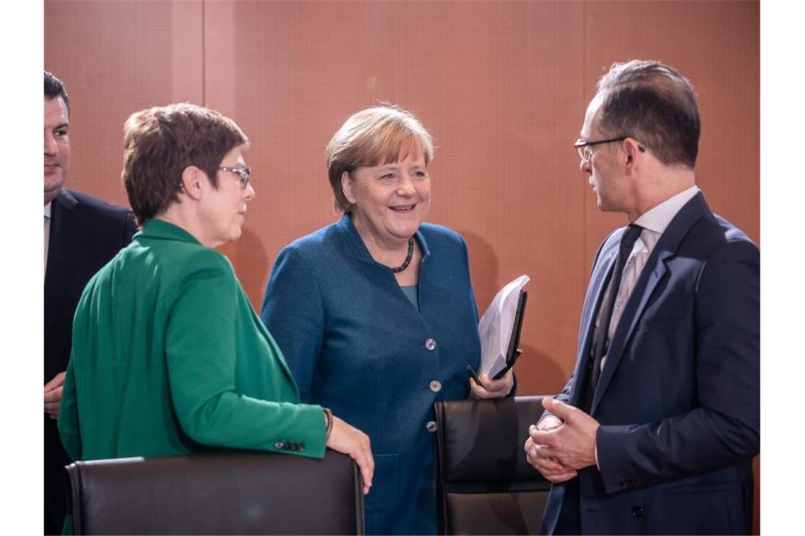 Bundeskanzlerin Angela Merkel (CDU) spricht mit Heiko Maas (SPD, r), Außenminister, zu Beginn der Sitzung des Bundeskabinetts im Kanzleramt während daneben Annegret Kramp-Karrenbauer (CDU, 2.v.l), Bundesministerin der Verteidigung und Hubertus Heil (SPD, l), Bundesminister für Arbeit und Soziales, stehen. Foto: Michael Kappeler/dpa