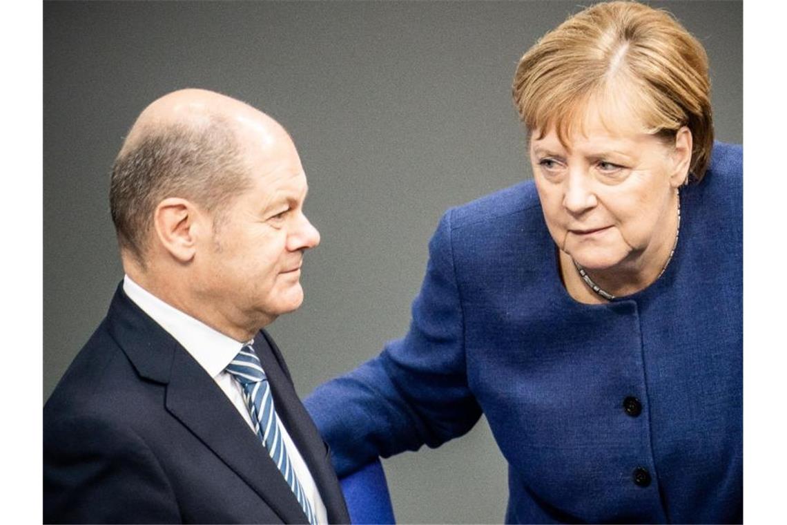 Bundeskanzlerin Angela Merkel (CDU), spricht mit Olaf Scholz (SPD), Bundesfinanzminister, im Bundestag. Foto: Michael Kappeler/dpa