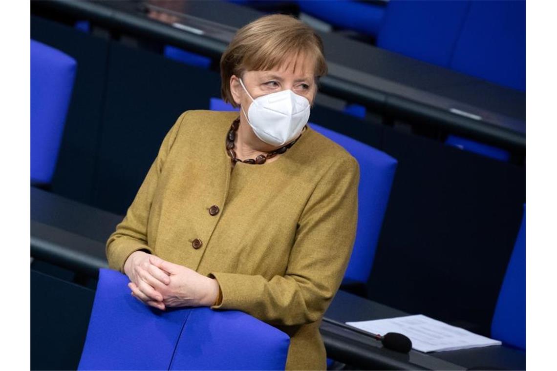 Nach schwierigem Start: Impfgipfel soll Fortschritte bringen Bundeskanzlerin Angela Merkel (CDU) steht zu Beginn der Plenarsitzung im Deutschen Bundestag mit Schutzmaske an ihrem Platz. Foto: Bernd von Jutrczenka/dpa