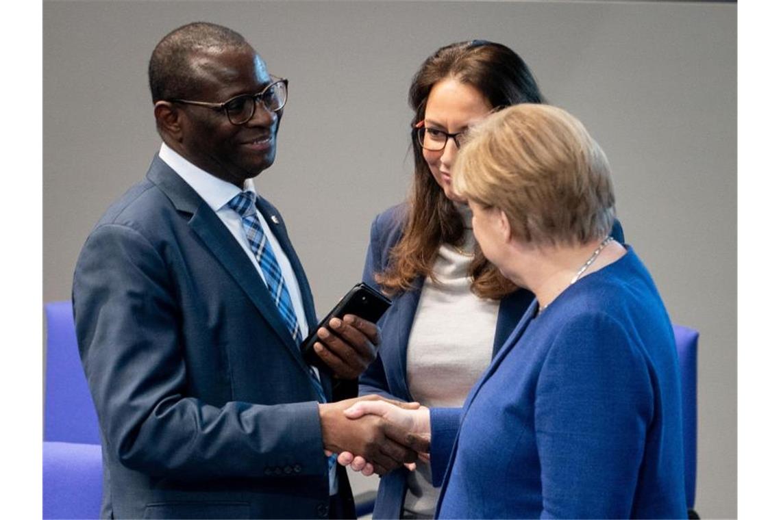 Bundeskanzlerin Angela Merkel (CDU) stellt sich hinter den SPD-Bundestagsabgeordneten Karamba Diaby (li), nachdem dessen Bürgerbüro angegriffen wurde. Foto: Kay Nietfeld/dpa