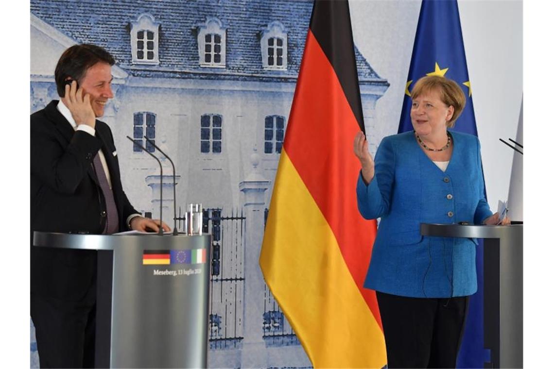 Merkel und Conte wollen wuchtige Antwort auf Corona-Krise Bundeskanzlerin Angela Merkel (CDU) und Giuseppe Conte, Ministerpräsident von Italien, scherzen während einer Pressekonferenz auf Schloss Meseberg. Foto: Tobias Schwarz/AFP pool/dpa