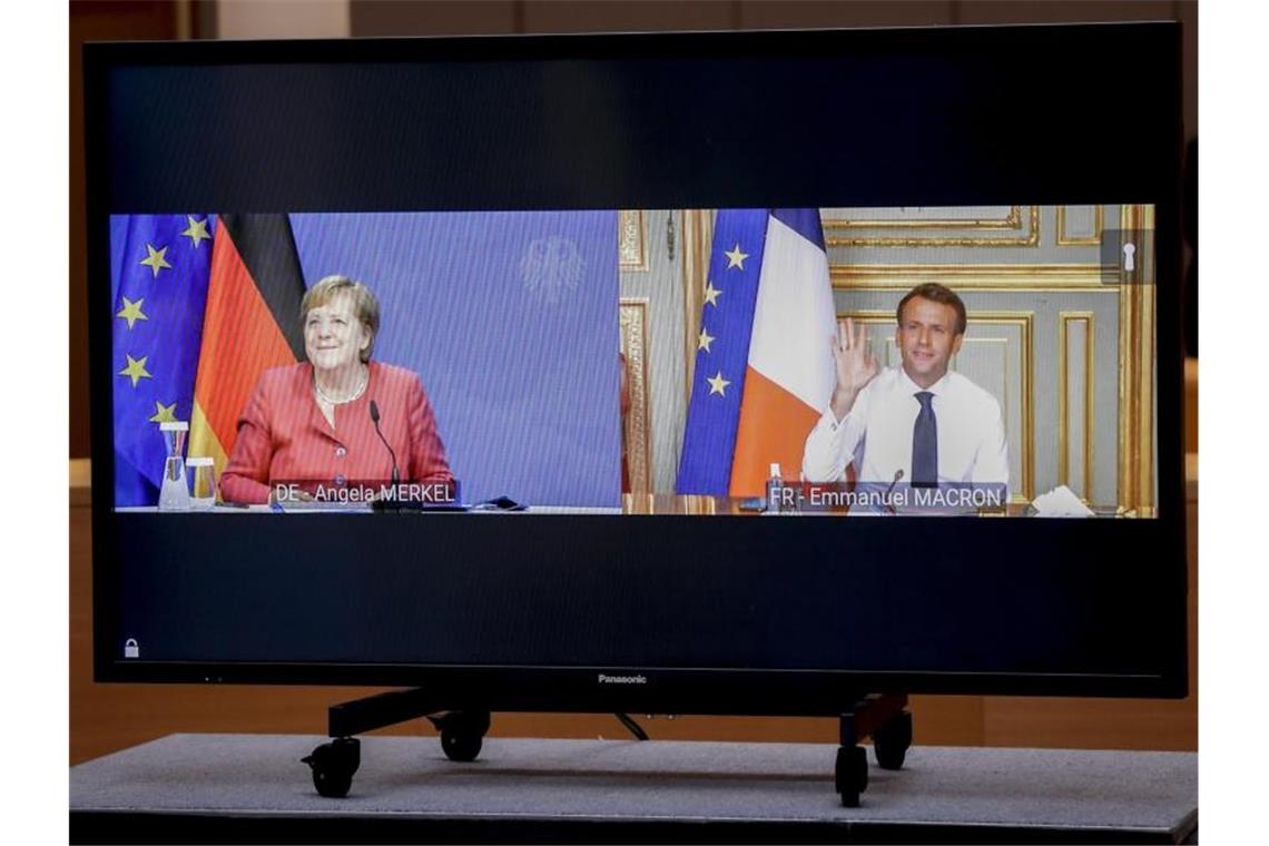Bundeskanzlerin Angela Merkel (l) und Frankreichs Staatspräsident Emmanuel Macron sind während einer Videokonferenz vor dem EU-Gipfel in Brüssel auf einem Bildschirm zu sehen. Foto: Olivier Hoslet/Pool EPA/AP/dpa
