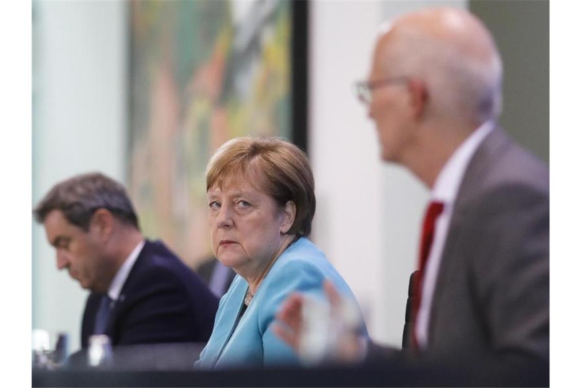 Bundeskanzlerin Angela Merkel nimmt zusammen mit dem bayerischen Ministerpräsident Markus Söder und Hamburgs Erstem Bürgermeister Peter Tschentscher nach Abschluss der Beratungen an einer Pressekonferenz teil. Foto: Markus Schreiber/AP-Pool/dpa