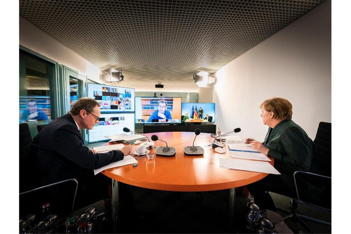 Bundeskanzlerin Angela Merkel und Berlins Regierender Bürgermeister Michael Müller sitzen gemeinsam im Kanzleramt bei der Videokonferenz mit den Ministerpräsidenten der Länder. Foto: Steffen Kugler/Bundesregierung/dpa