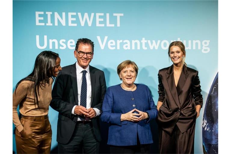 Bundeskanzlerin Angela Merkel und Entwicklungsminister Gerd Müller stehen zusammen mit den Ministeriums-Botschafterinnen Sara Nuru (l) und Toni Garrn (r) bei der Veranstaltung „Eine Welt - Unsere Verantwortung“. Foto: Michael Kappeler/dpa