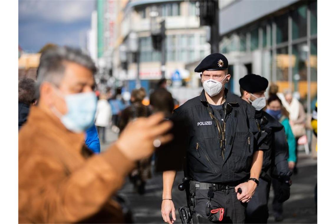 Bundespolizisten kontrollieren auf einer Einkaufsstraße in Berlin die Einhaltung der Maskenpflicht. Foto: Christoph Soeder/dpa