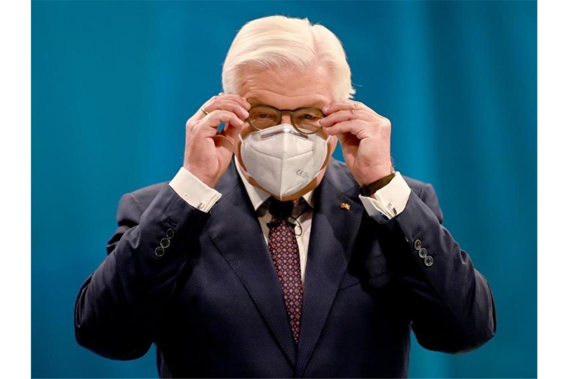 Bundespräsident Frank-Walter Steinmeier setzt sich einen Mund-Nasen-Schutz auf. Foto: Britta Pedersen/dpa/Archivbild