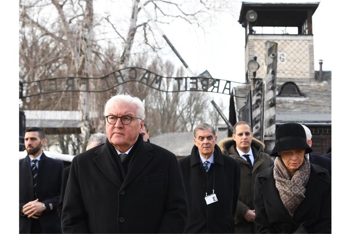 Warnungen und Mahnungen zur Gedenkfeier in Auschwitz Bundespräsident Frank-Walter Steinmeier und seine Frau Elke Büdenbender vor dem Eingang zum Konzentrationslager Auschwitz mit dem Schriftzug „Arbeit macht frei“. Foto: Britta Pedersen/dpa-Zentralbild/dpa