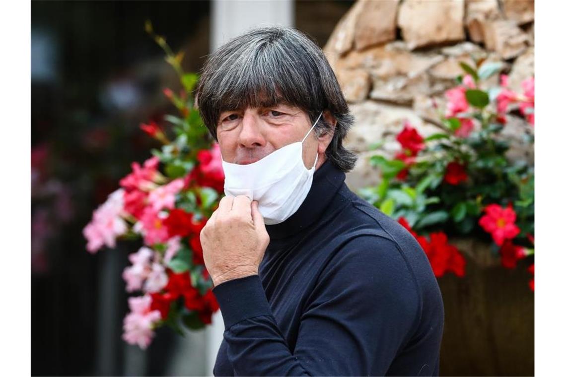 Löw beginnt Vorbereitung für Neustart: Alle Spieler im Hotel Bundestrainer Jogi Löw zieht bei der Ankunft im Wald-Hotel seine Maske vom Gesicht. Foto: Christoph Schmidt/dpa