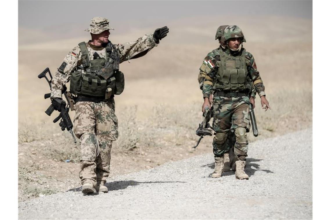 Bundesregierung prüft Teilrückzug der Soldaten aus Nordirak Bundeswehrsoldaten und kurdische Peshmerga Soldaten gehen in der Ausbildungseinrichtung Bnaslawa bei einer Übung am Rand einer Straße entlang. Nun prüft die Bundesregierung den Teilrückzug der Soldaten aus Erbil. Foto: Michael Kappeler/dpa
