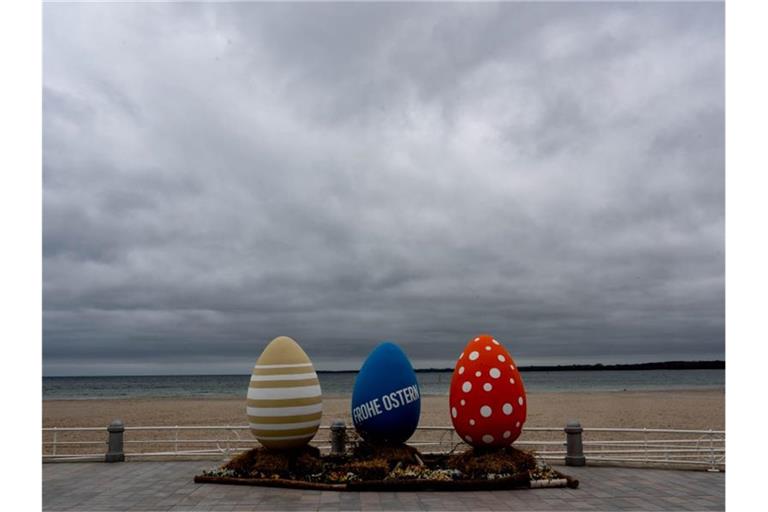 Bunt bemalte überdimensionale Ostereier stehen am wolkenverhangenen Strand von Travemünde. Foto: Axel Heimken/dpa