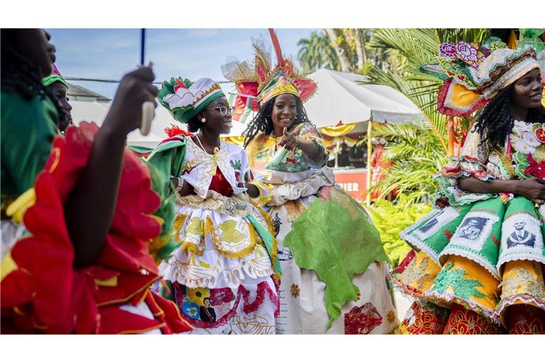 Bunt gekleidete Gäste feiern im Garten des Präsidentenpalastes von Suriname.