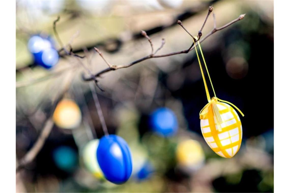 Bunte Ostereier hängen an einem Baum in einem Garten. Foto: Hauke-Christian Dittrich/dpa/Symbolbild