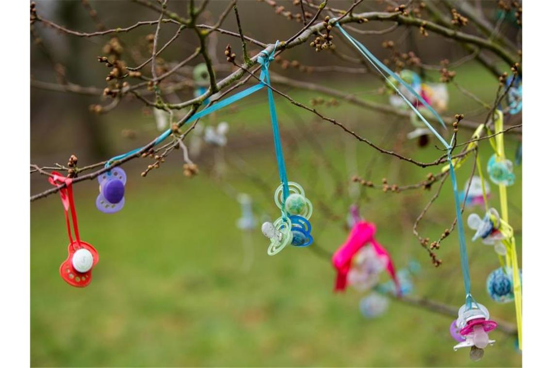 Bunte Schnuller hängen an einem Baum. Früher wurden mehr Kinder im Frühjahr geboren, heute im Sommer. Doch warum?. Foto: Hauke-Christian Dittrich/dpa