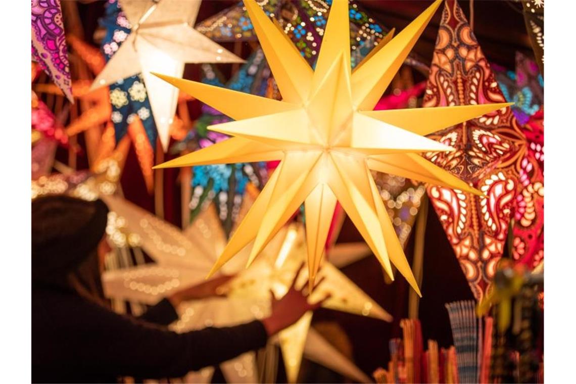 Bunte Weihnachtssterne werden an einem Stand auf dem Weihnachtsmarkt angeboten. Foto: Friso Gentsch/dpa