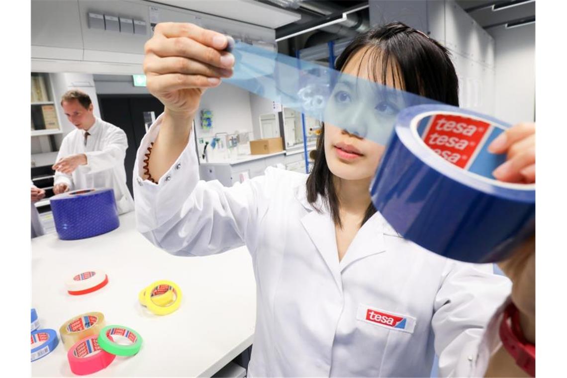 Vom Reifenflicken zum Handy: 125 Jahre technisches Klebeband Cai Rong Lim (r), damals Bereichsleiterin in der Produkt- und Technologie-Entwicklung bei Tesa, prüft in einem Tesa-Labor in Norderstedt (Schleswig-Holstein) bei Hamburg ein transparentes Klebeband. Foto: picture alliance / Christian Charisius/dpa