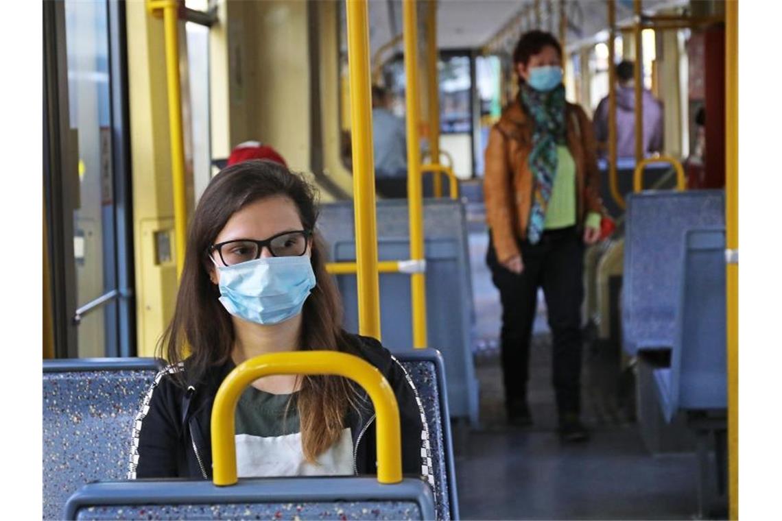 Cathrine sitzt mit einer Schutzmaske in einer Straßenbahn. Foto: Oliver Berg/dpa
