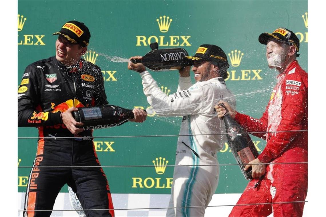 Champagnerdusche: Sieger Lewis Hamilton (M) mit Max Verstappen (l) und Sebastian Vettel auf dem Podium in Budapest. Foto: Laszlo Balogh/AP