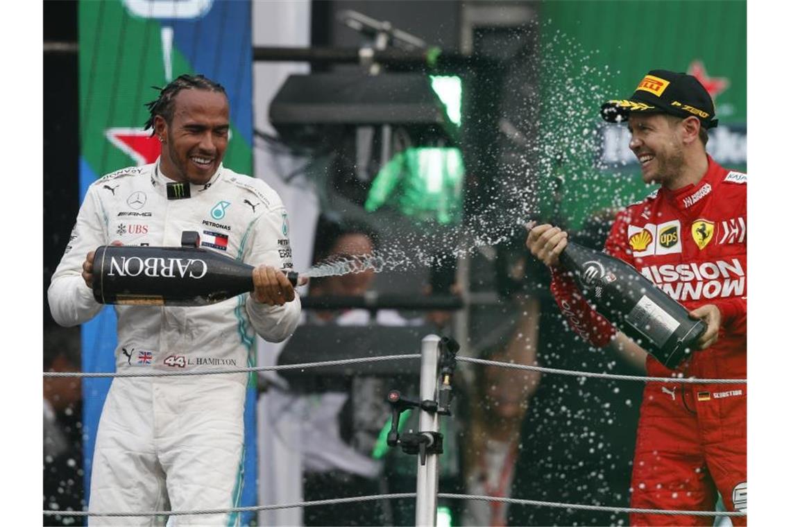 Champus für den Sieger: Lewis Hamilton feiert, Sebastian Vettel zwangsläufig mit. Foto: Rebecca Blackwell/AP/dpa