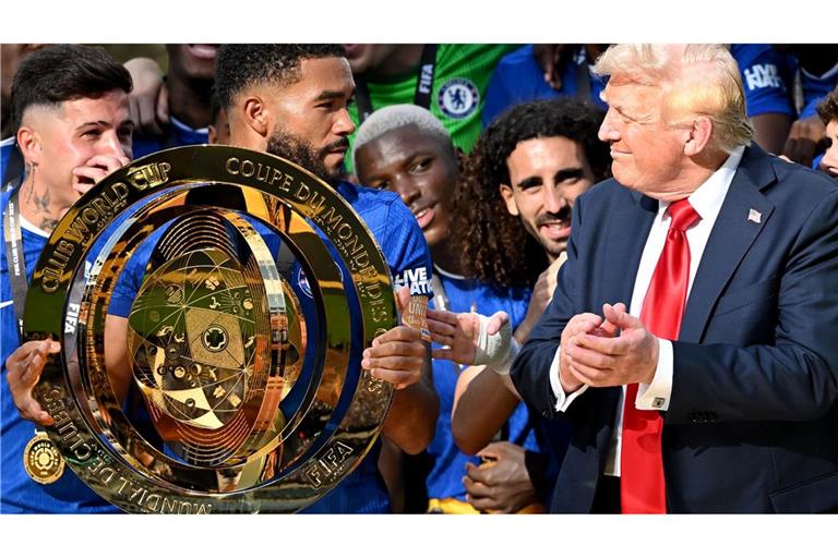 Chelseas Kapitän Reece James (l/vorn) hält auf dem Siegerpodest die Trophäe in den Händen und schaut irritiert zu US-Präsident Donald Trump.