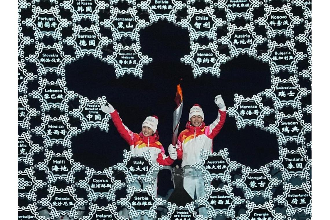 Uigurin entzündet olympisches Feuer Chinas Zhao Jiawen (r) und Yilamujiang Dinigeer haben das olympische Feuer für die Winterspiele in Peking entzündet. Foto: Michael Kappeler/dpa