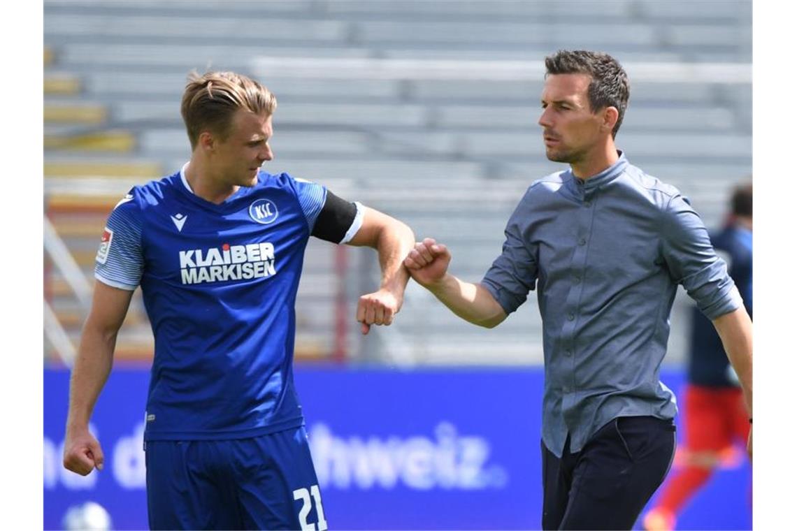 Christian Eichner, Trainer von Karlsruher SC, klatscht bei Spielende mit Marco Thiede (l) ab. Foto: Uli Deck/dpa-Pool/dpa