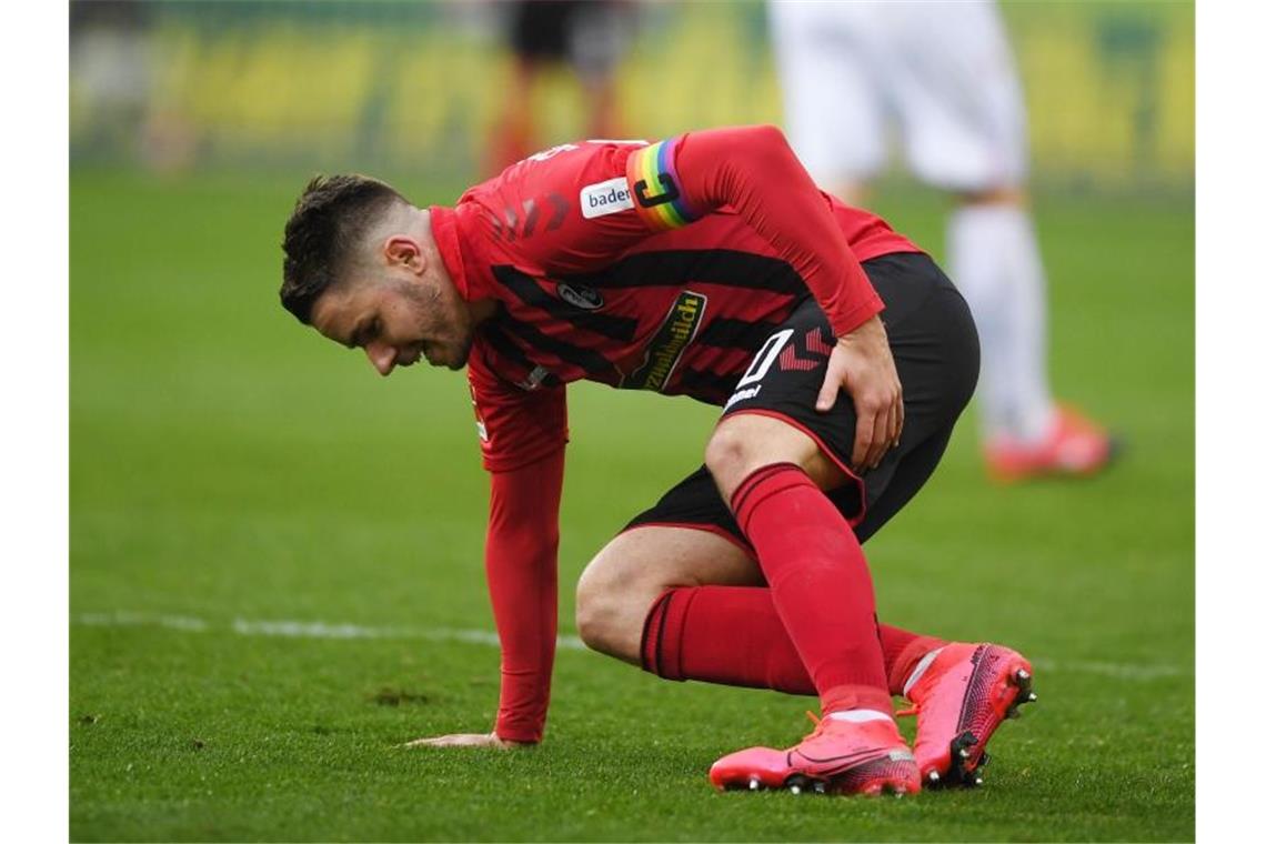 Christian Günter von Freiburg setzt sich nach einem Foul verletzt auf den Rasen. Foto: Patrick Seeger/dpa