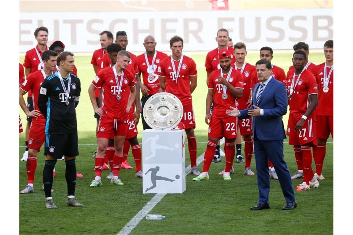 Christian Seifert überreicht nach einer denkwürdigen Saison den Bayern-Profis die Meisterschale. Foto: Kai Pfaffenbach/Reuters-Pool/dpa